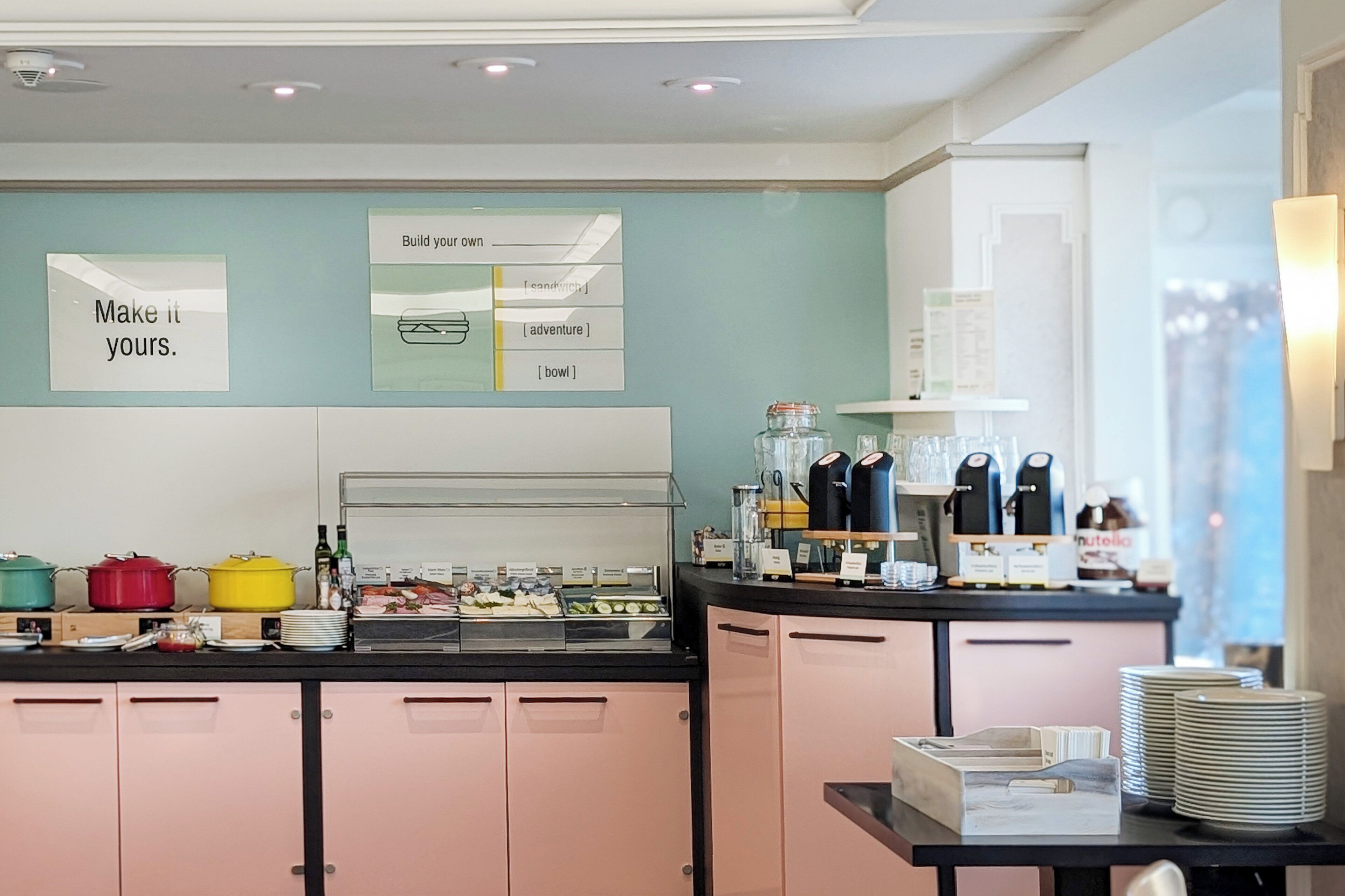 A buffet area with various food items, a coffee station, and a counter with plates and cups.