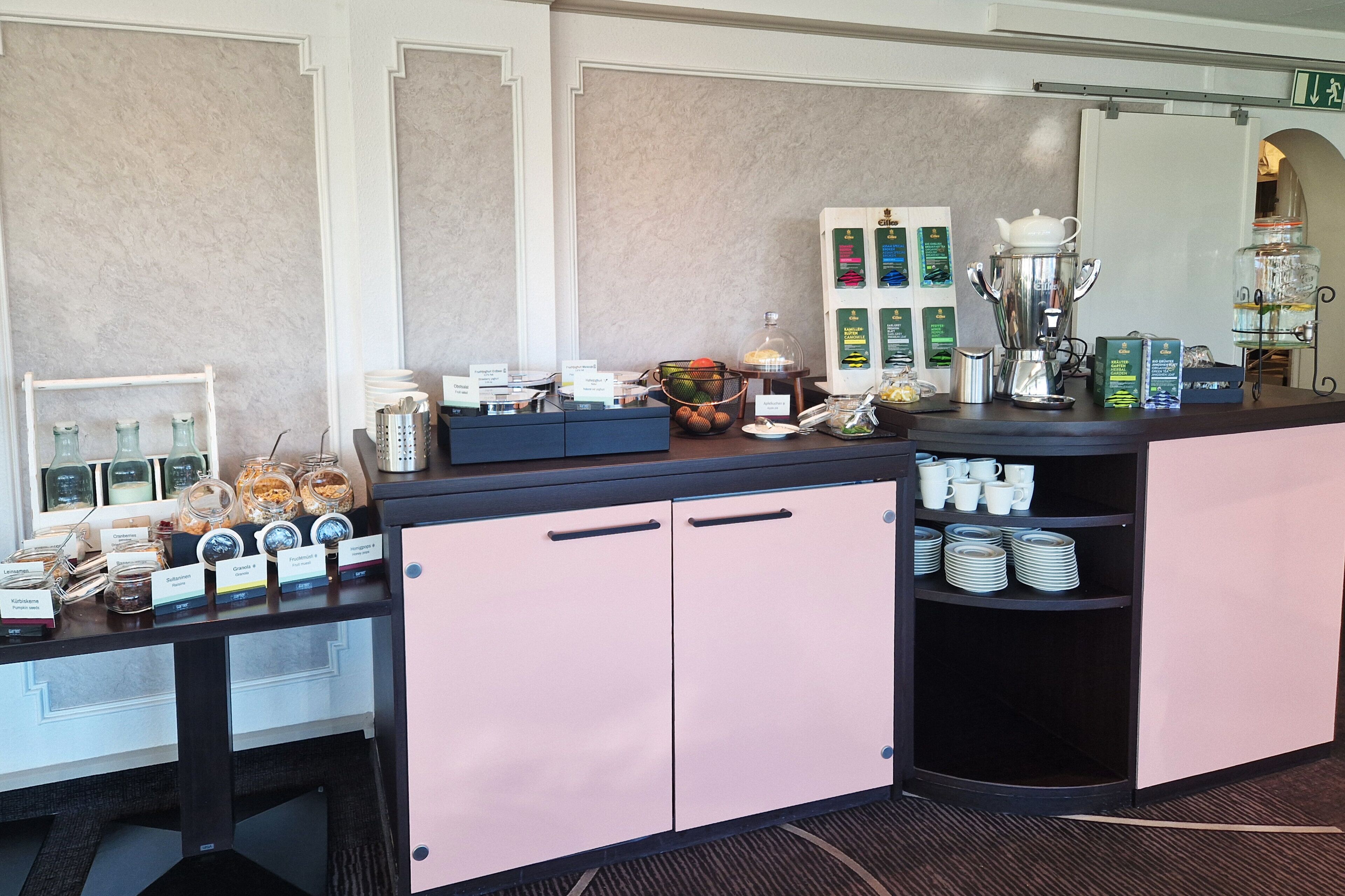 A hotel reception area with a counter displaying various food items and a coffee station.