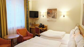 A hotel room with two beds, a desk, a chair, a television, and a painting on the wall.