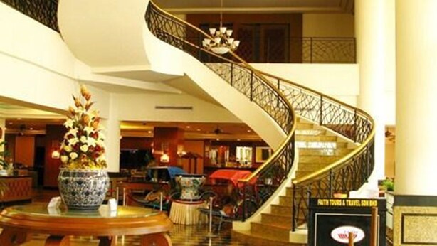 Um hall com uma escadaria imponente, um lustre e um piso xadrez.