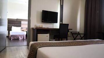 A hotel room with a bed, a desk with a computer, a television, and a chair.