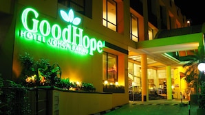 Exterior do GoodHope Hotel Johor Bahru, com letreiro de neon, entrada coberta e plantas em vasos.