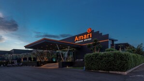 Un hotel moderno con un llamativo letrero de Amari Buriram United, que cuenta con una entrada cubierta y jardines.