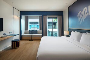 A hotel room with a large bed, a seating area with a view, a TV, and a small table.