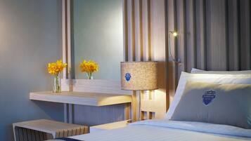 A hotel room with a bed, a bedside table with a lamp, and a mirror.