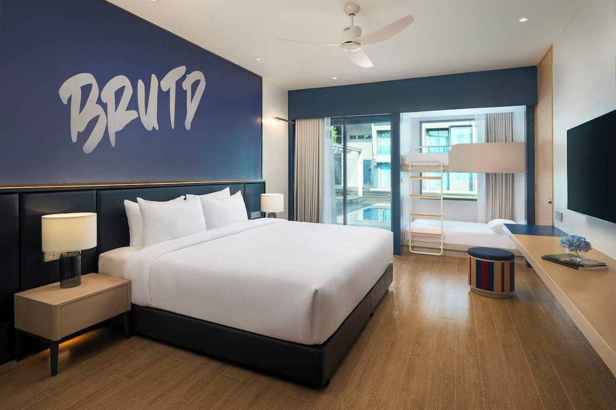 A hotel room with a bed, a nightstand, a lamp, a TV, a ceiling fan, and a view of the outside.