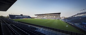 Un estadio con múltiples niveles de butacas, un amplio campo verde y varios anuncios publicitarios.
