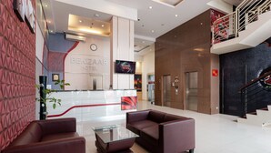 Eine moderne Hotelhalle mit Empfangstresen, Sitzgelegenheiten und einer Treppe.