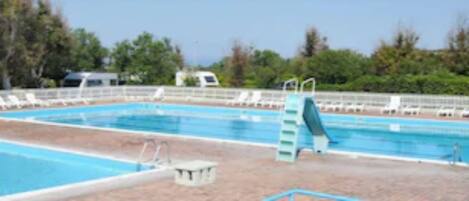 Una piscina con dos carriles, rodeada de sillas de descanso y un puesto de socorrista.