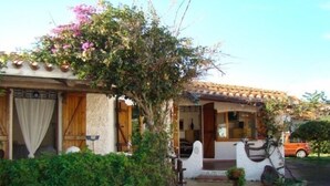 A traditional house with a tiled roof, a wooden door, and a small porch with a potted plant. - Village Camping La Foce (Valledoria)