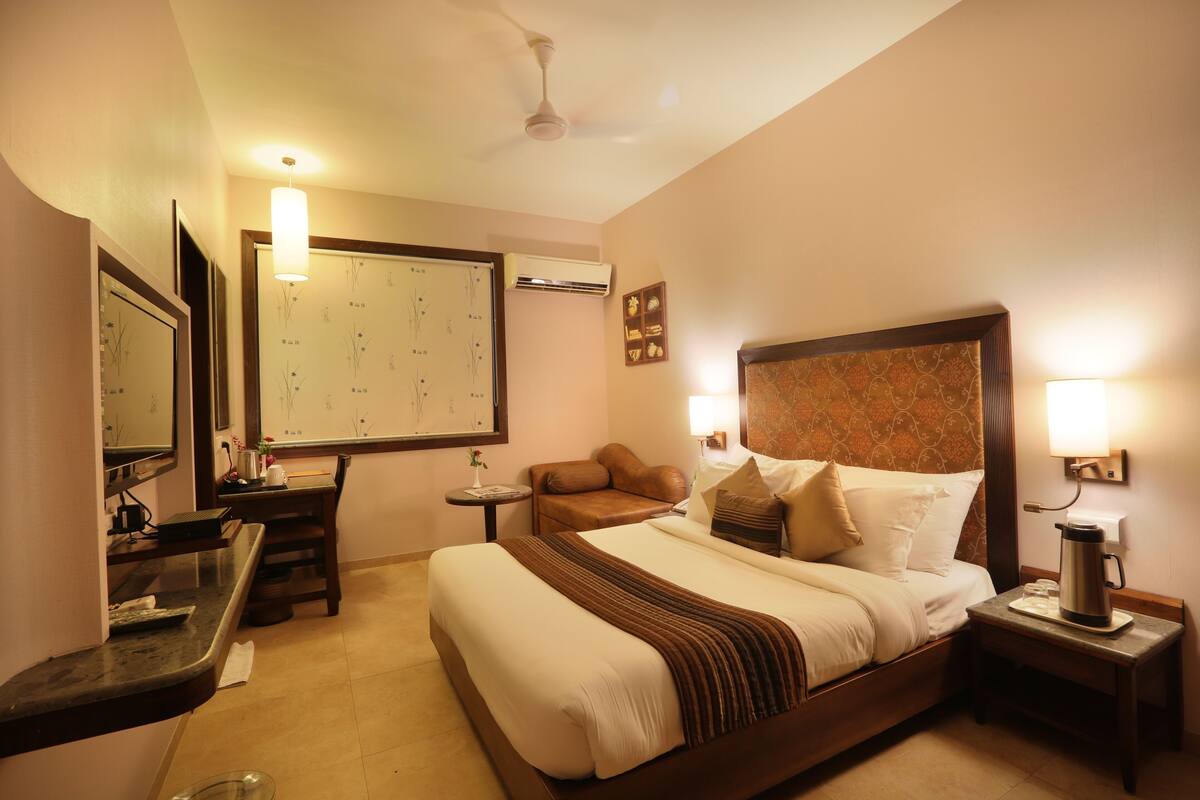 Quarto de hotel com cama, mesa de cabeceira, abajur e ar condicionado na parede.