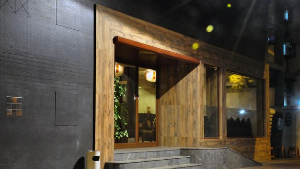 A modern building with a wooden facade, large windows, and a staircase leading to the entrance. - Abbott Hotel (Navi Mumbai)