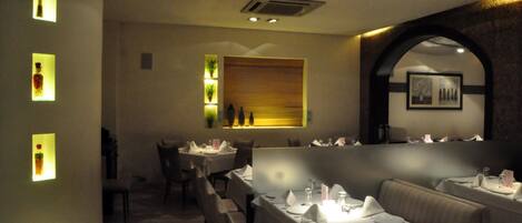 Un restaurant avec des tables dressées pour le service, un mur décoratif en bois et un tableau encadré accroché au mur.