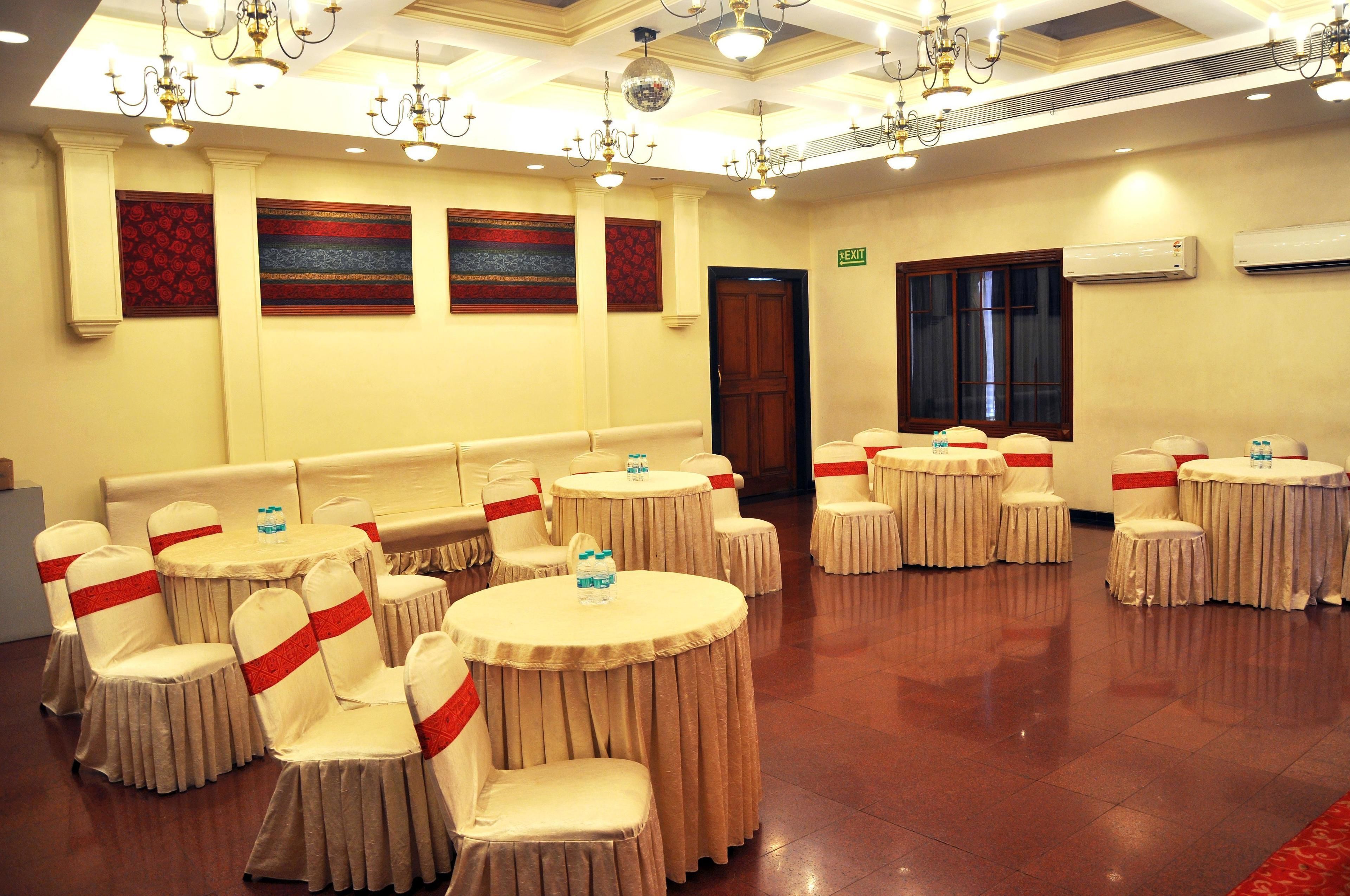 A banquet hall with round tables and chairs, a chandelier, and wall decorations.