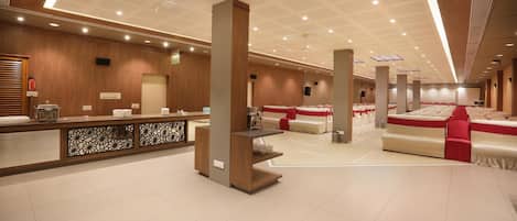 A spacious hotel lobby with a reception desk, seating area, and a stage.
