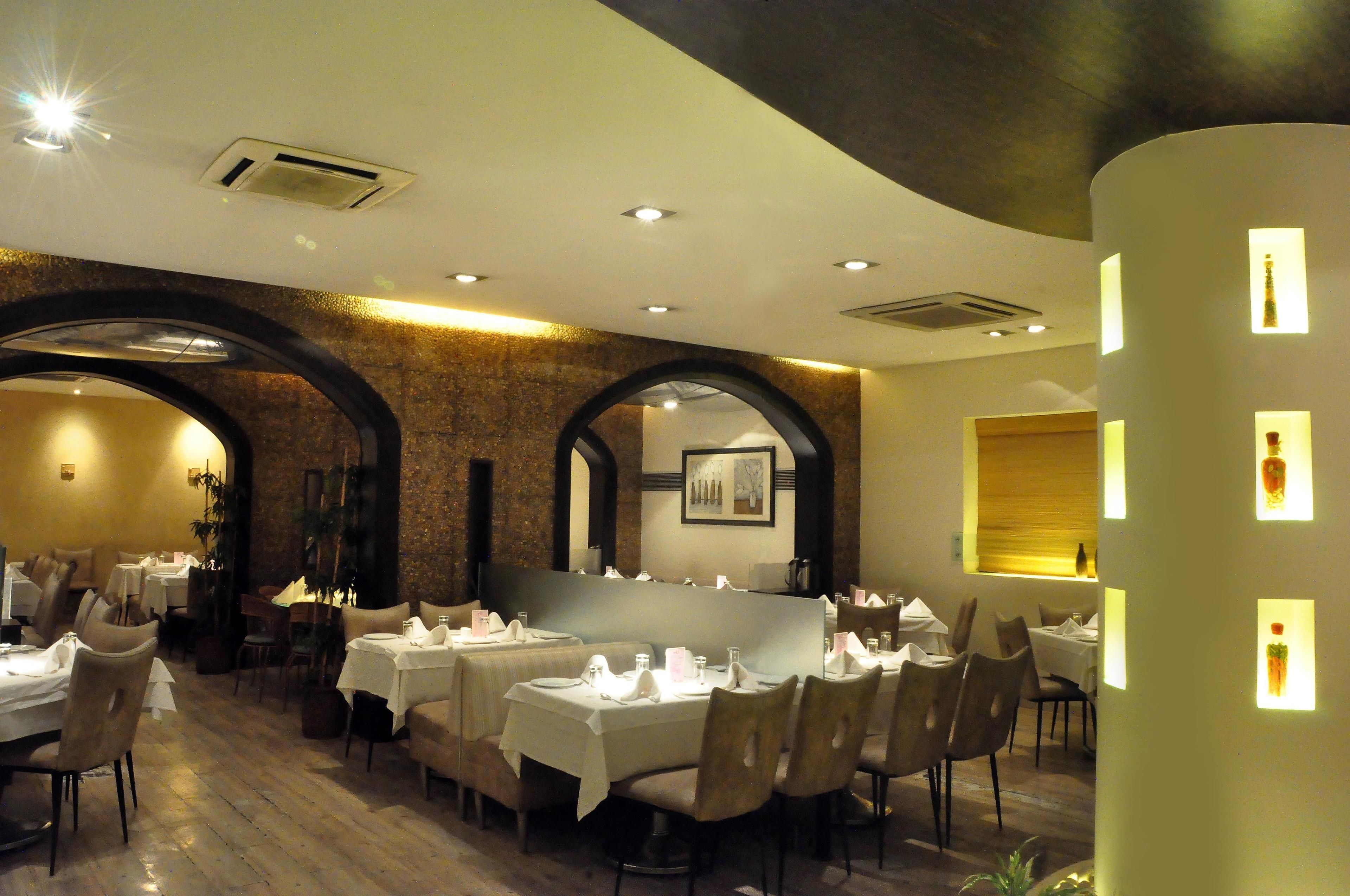 Un ristorante con tavoli apparecchiati, un muro in mattoni e un moderno design del soffitto.