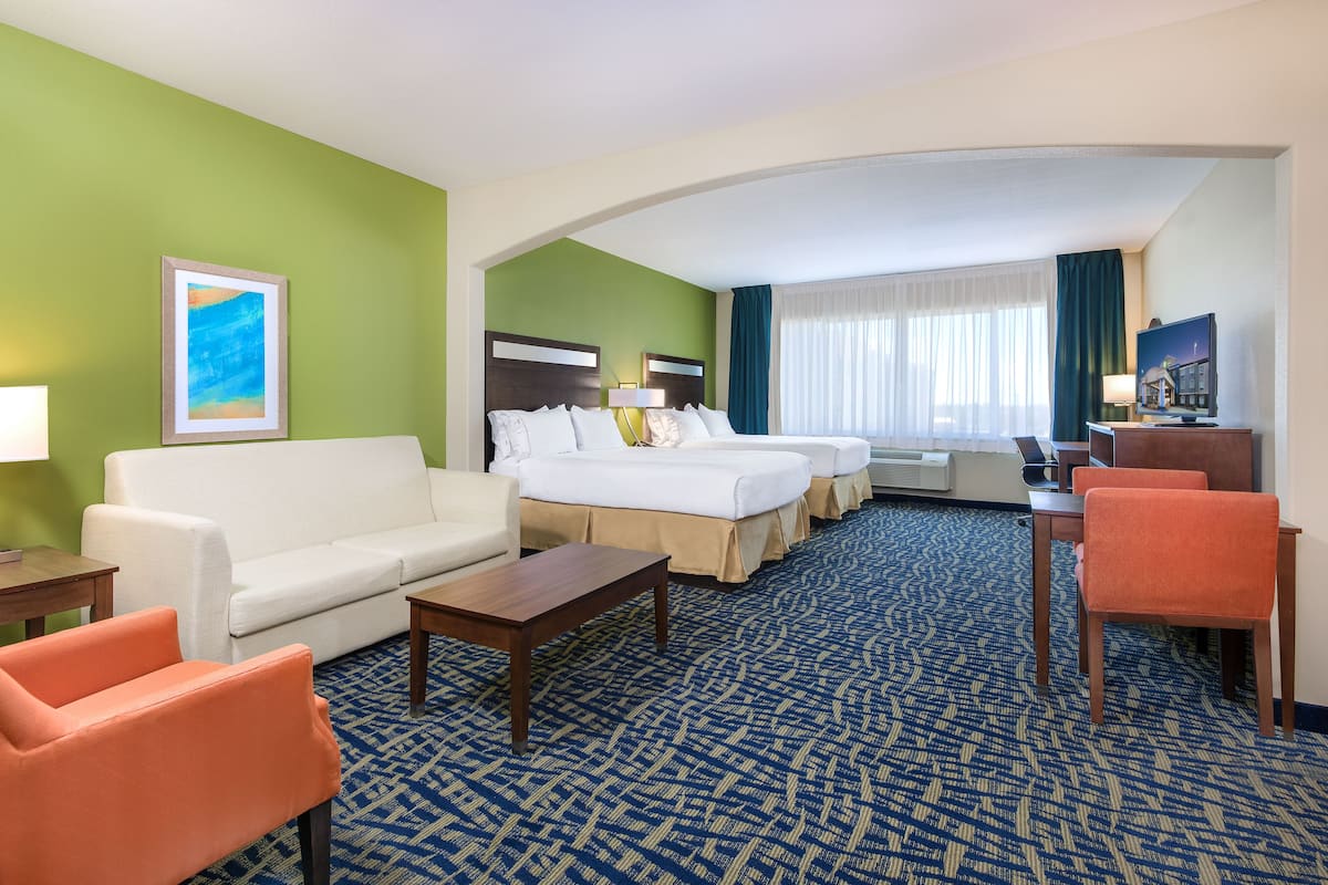 A hotel room with a bed, a sofa, a desk, and a chair.