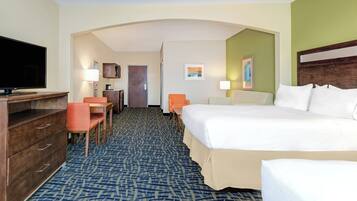 A hotel room with a bed, a desk, a chair, a television, and a door.