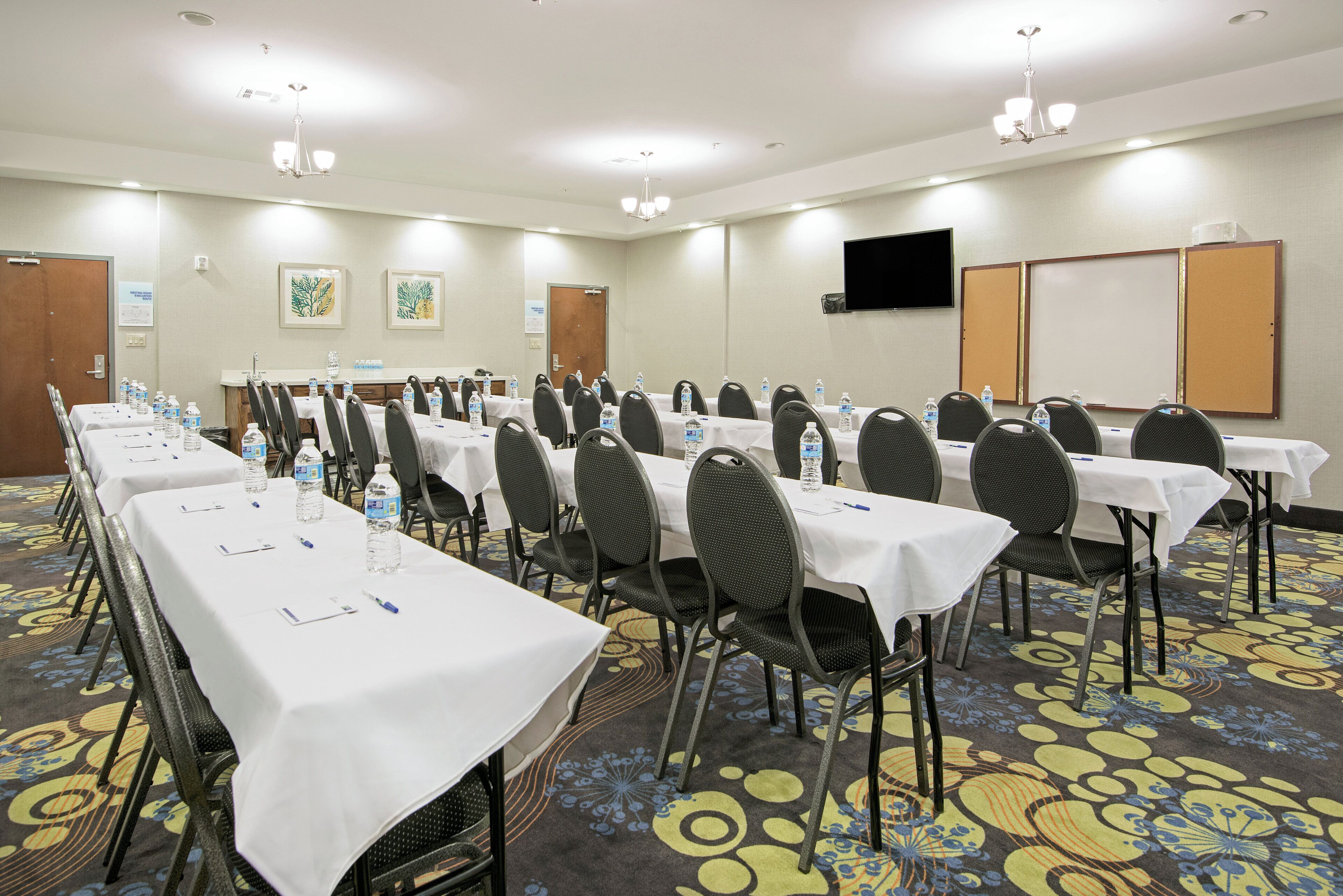 A conference room with long tables, chairs, water bottles, and a whiteboard.