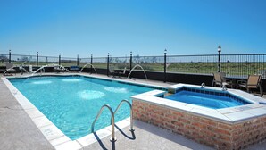 A swimming pool with a hot tub, surrounded by lounge chairs and a fence. - Holiday Inn Express Hotel & Suites Monahans - I-20 by IHG (Monahans)