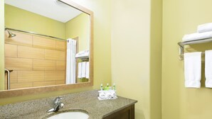 A bathroom with a granite sink, a mirror, a towel rack, and a shower area. - Holiday Inn Express Hotel & Suites Monahans - I-20 by IHG (Monahans)