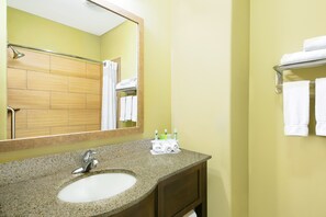 A bathroom with a granite sink, a mirror, a towel rack, and a shower area. - Holiday Inn Express Hotel & Suites Monahans - I-20 by IHG (Monahans)