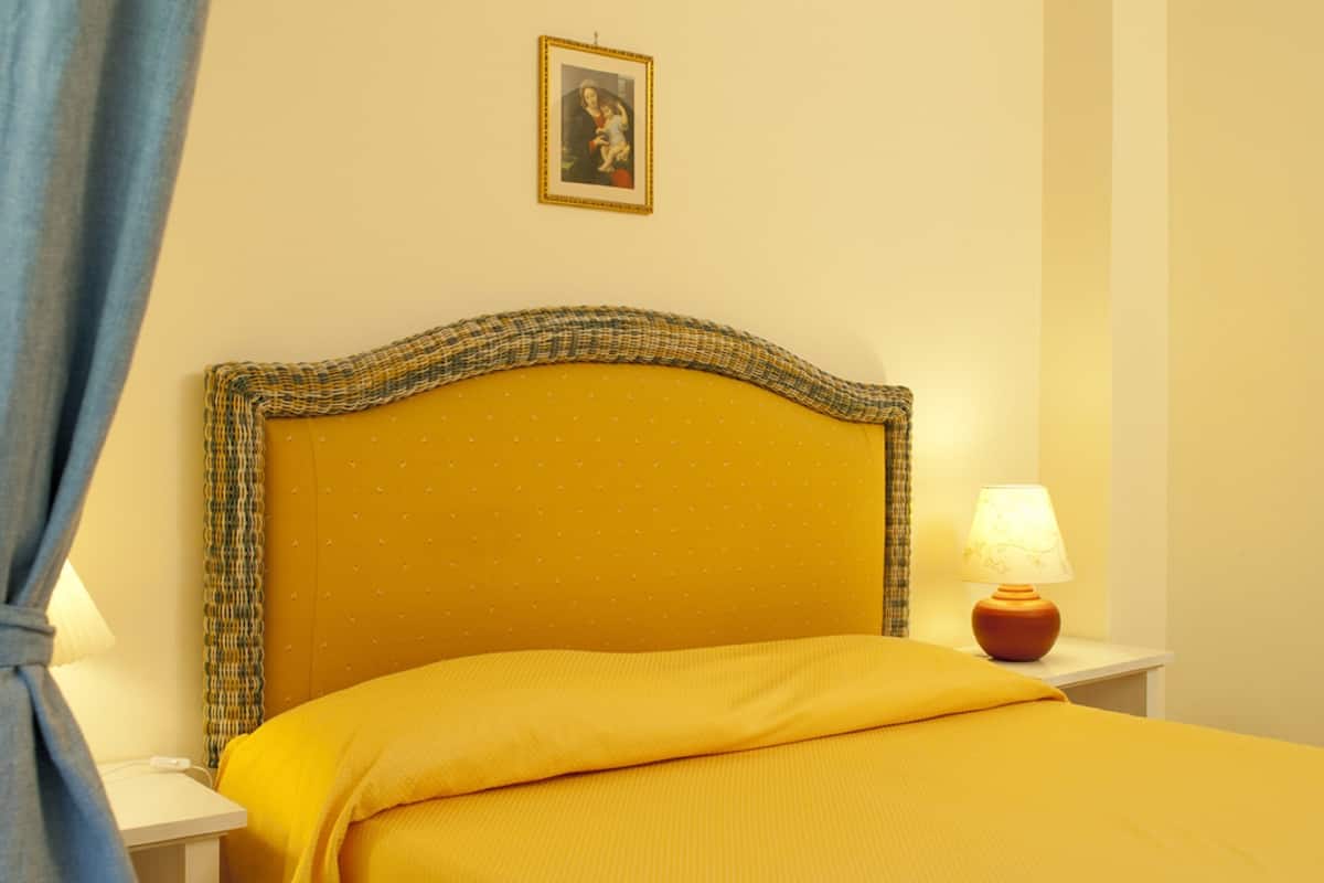 A room with a bed, a nightstand, a lamp, and a picture on the wall.