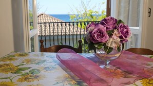 A table with a floral tablecloth, a glass vase with purple flowers, and a balcony with a view of the sea. - Hotel Paradiso Residence (Castellabate)