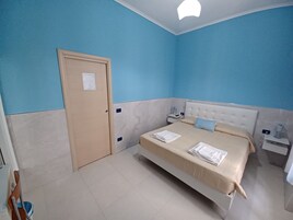 Een slaapkamer met een bed, nachtkastjes, een deur en een lamp.