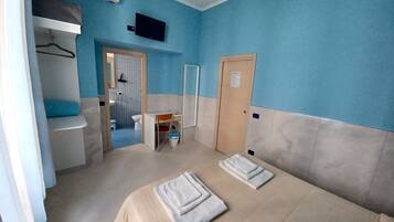 Une chambre avec deux lits, un bureau, une chaise, un lavabo et une douche.