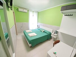 A hotel room with a bed, bedside table, and a desk with a chair.