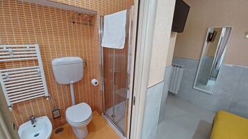Un baño con inodoro, bidé y zona de ducha.
