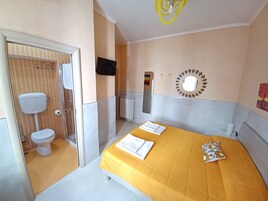Une chambre d’hôtel avec un lit, des toilettes, une douche et un téléviseur.