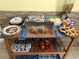 Une table de buffet proposant une variété de plats, notamment des gâteaux, des pâtisseries et des fruits.