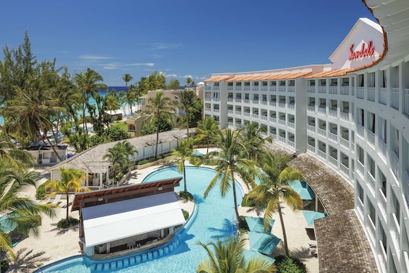 Un complexe hôtelier doté d’une piscine, de palmiers et d’une plage.