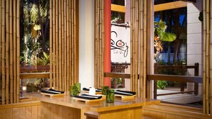 A sushi bar with a wooden counter, green glasses, and a sign with a sushi roll illustration. - Sandals Barbados - ALL INCLUSIVE Adults Only (Maxwell)