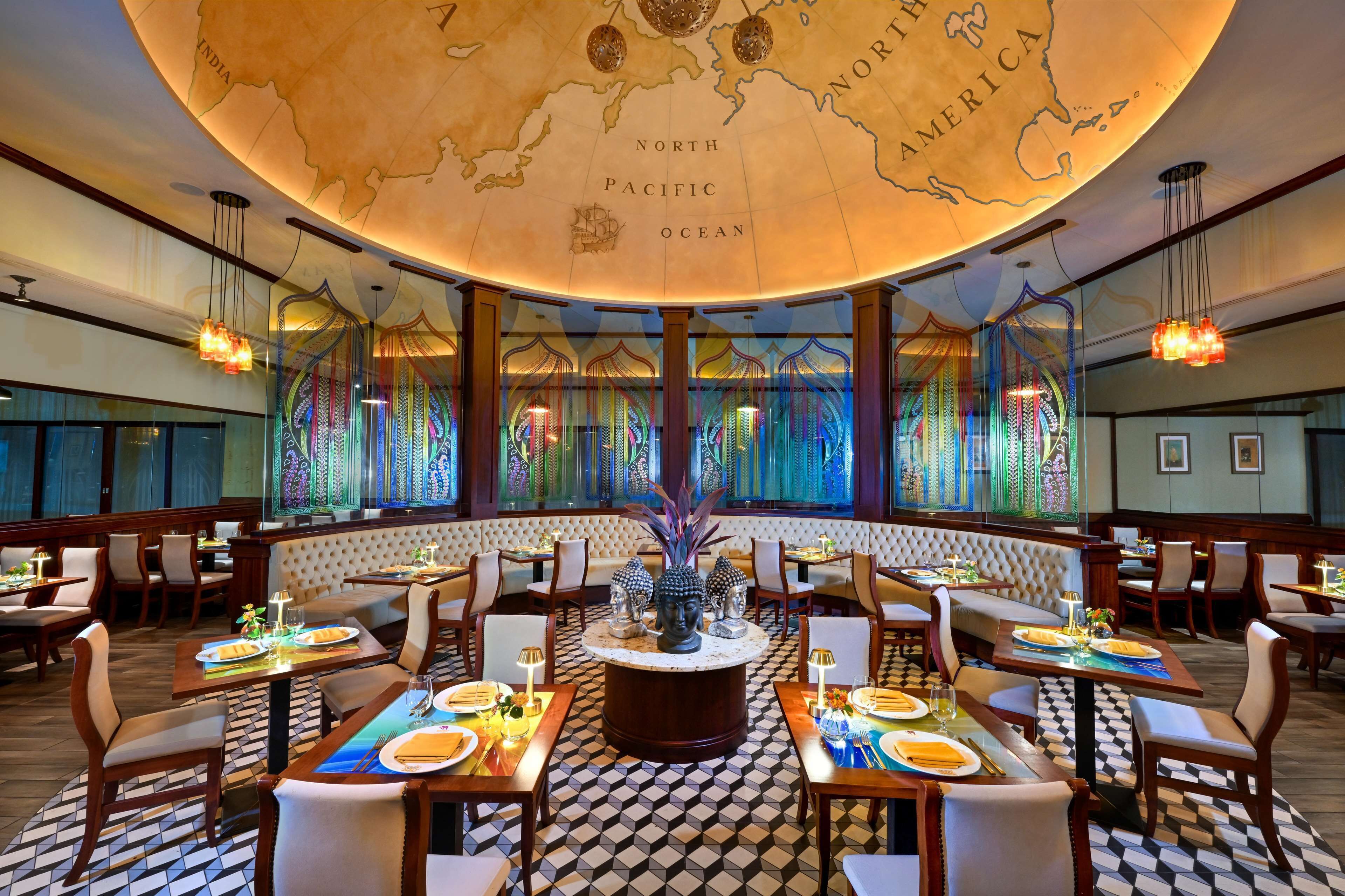 A restaurant with a central round table, multiple seating areas, and a ceiling map.