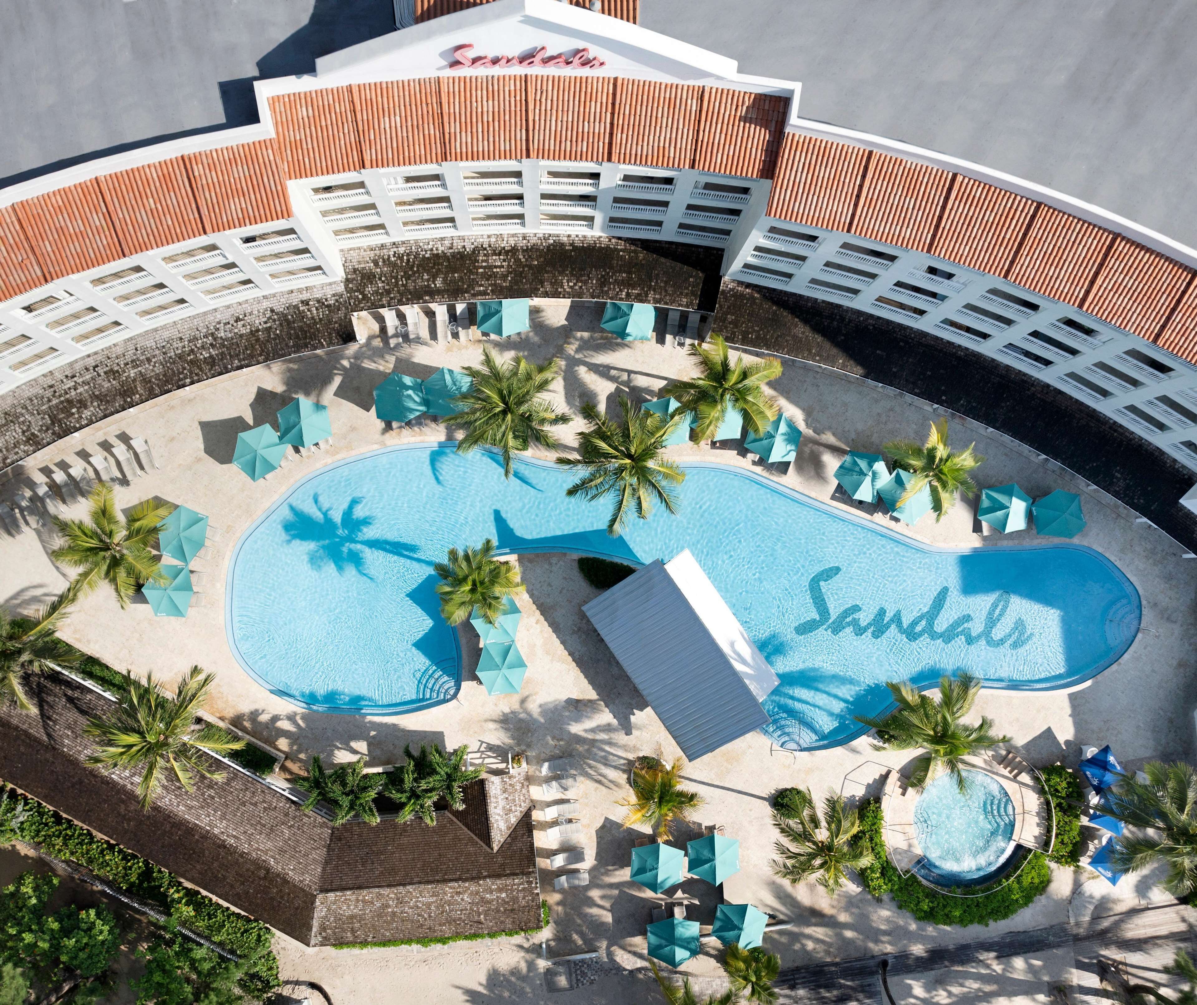 A resort with a large pool area, multiple lounge chairs, and palm trees.