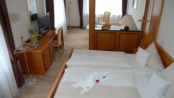 A hotel room with two beds, a desk with a computer, a lamp, and a chair.