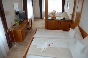 A hotel room with two beds, a desk with a computer, a lamp, and a chair. - Hotel Friesengeist (Wiesmoor)