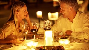 A couple dining at a table with candles, wine glasses, and a lit candle centerpiece. - Hotel Landhaus Milser (Duisburg)