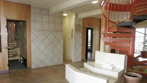 A spacious lobby with a modern staircase, a reception desk, and a potted plant. - Hotel Landhaus Milser (Duisburg)