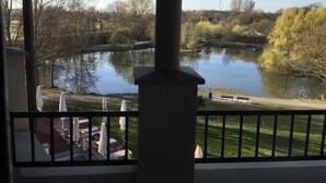 A view from a balcony overlooking a lake with trees and a bridge in the background. - Hotel Landhaus Milser (Duisburg)