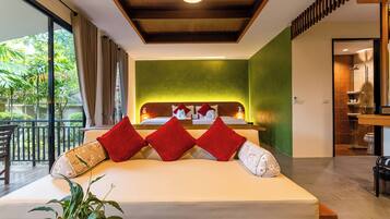 A modern hotel room with a large bed, a green accent wall, and a balcony with a view of greenery.