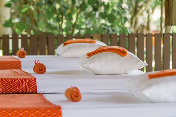 Une chambre d’hôtel bien aménagée, avec un banc en bois et des coussins blancs agrémentés de touches d’orange.