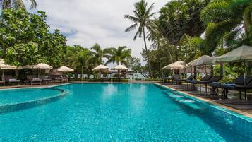 Relax by the serene pool surrounded by lush tropical vegetation and lounge chairs.