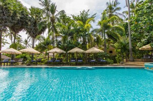 Una piscina al aire libre, sombrillas, sillones reclinables de piscina