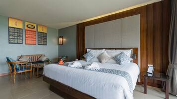 A hotel room with a large bed, a wooden headboard, a seating area with a chair and table, and a wall-mounted artwork.