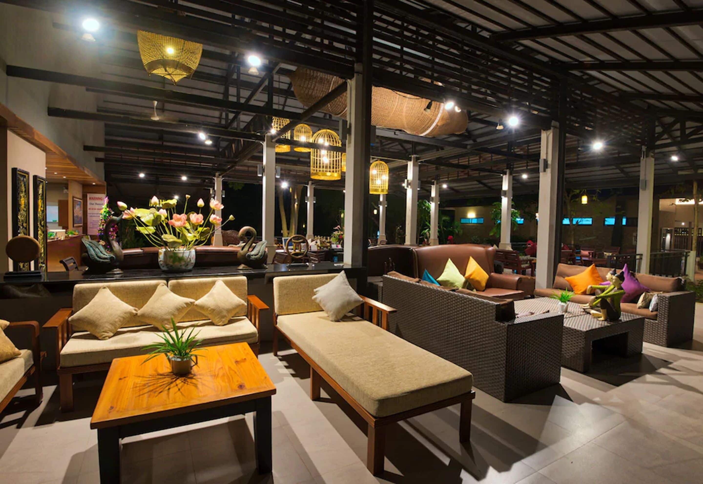 A spacious lounge area with multiple seating options including sofas and chairs, a central coffee table, and decorative elements like hanging baskets and a large plant.