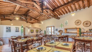 Un restaurante con mesas y sillas de madera, un techo alto de madera y diversos adornos en las paredes, incluyendo una planta y un estante con frascos.